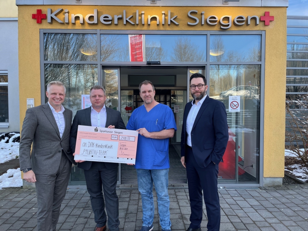 Von links nach rechts: Sebastian Weber, Tobias Weber (Geschäftsführung DATASEC), Oberarzt Markus Linke (DRK-Kinderklinik Siegen), und Tobias Wilsmann (Geschäftsführung DATASEC) bei der Übergabe des Spendenschecks über 2.500 Euro für das Kinder-Palliativteam der DRK-Kinderklinik in Siegen. Das Bild wurde vor dem Eingang der Klinik aufgenommen.